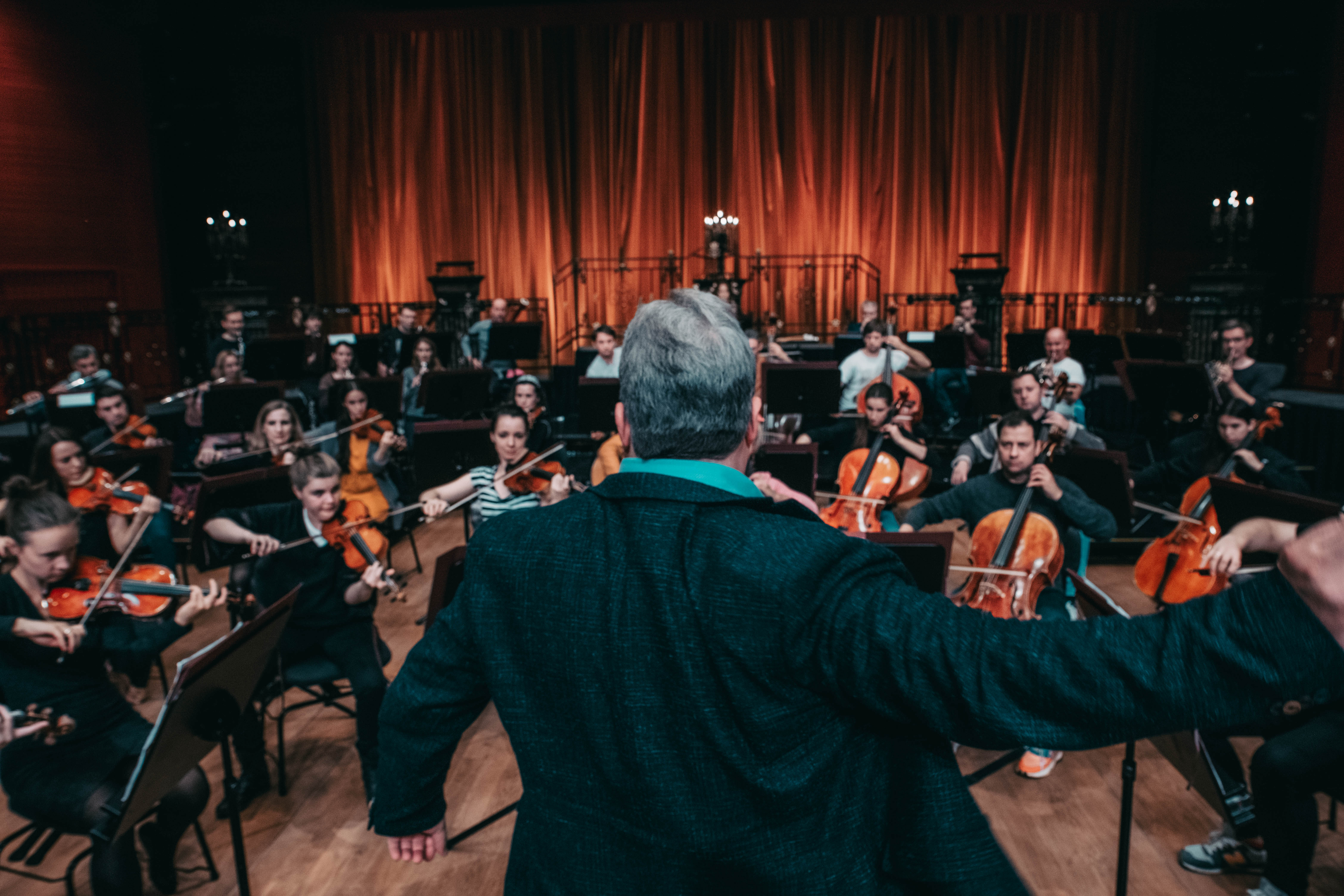 Conductor leading the orchestra — warm stage lights